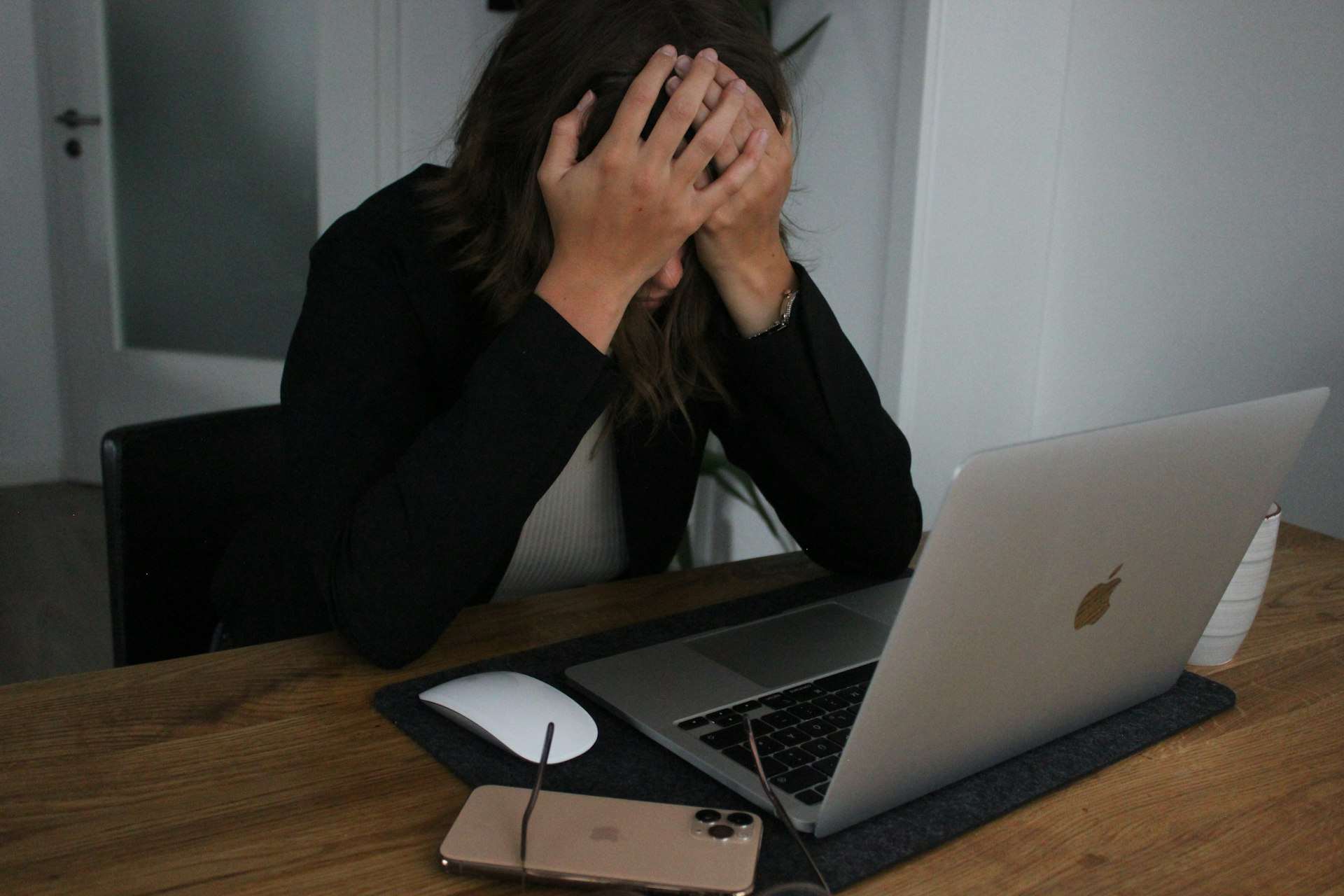 a woman covering her face while looking at a laptop